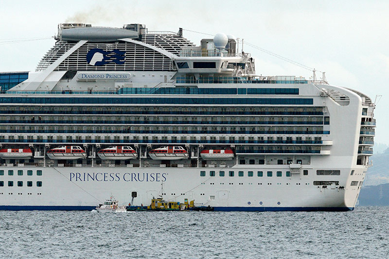 A small boat navigates near a cruise ship Diamond Princess anchoring off the Yokohama Port