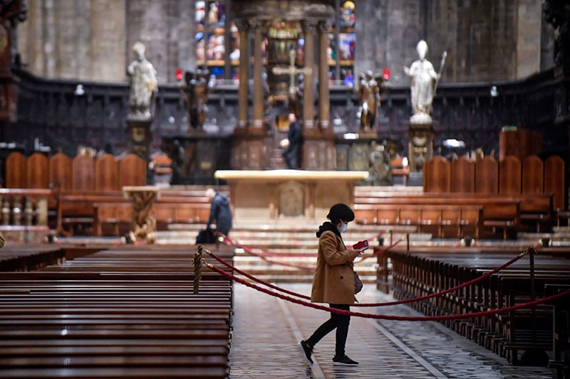A tourist wearing a face mask walks inside the Duomo gothic cathedral as it reopened to the public after being closed due to 