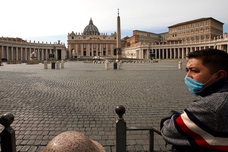 A man wears a mask as he looks at an empty St Peters Square after the Vatican erected a new barricade at the edge of the sq