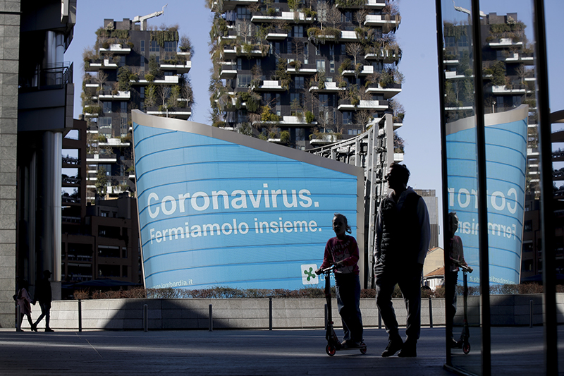 A man and a girl in Lombardy in front of an advertisement reading in Italian Coronavirus lets stop it together  