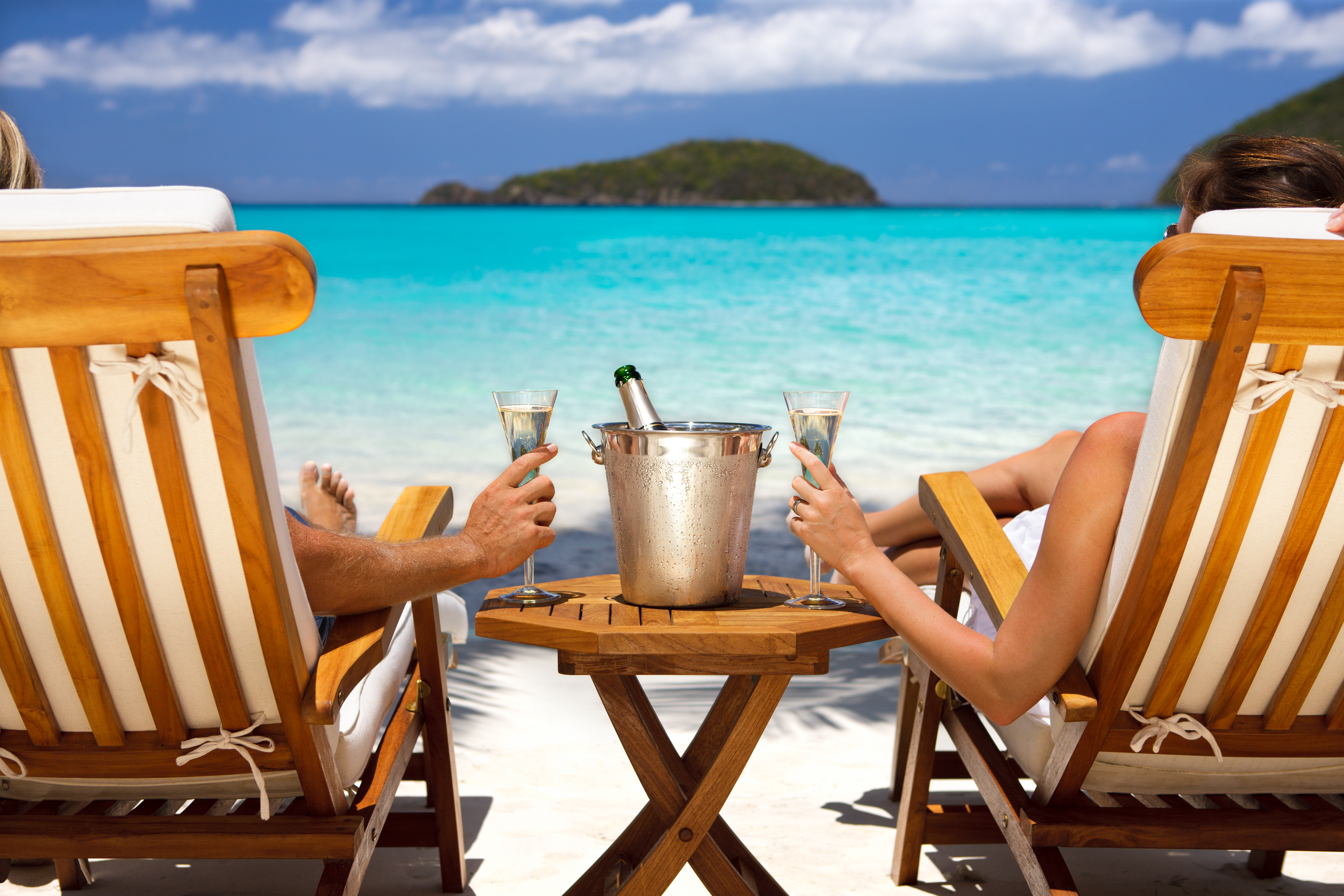 honeymoon couple in recliners drinking champagne at a Caribbean beach