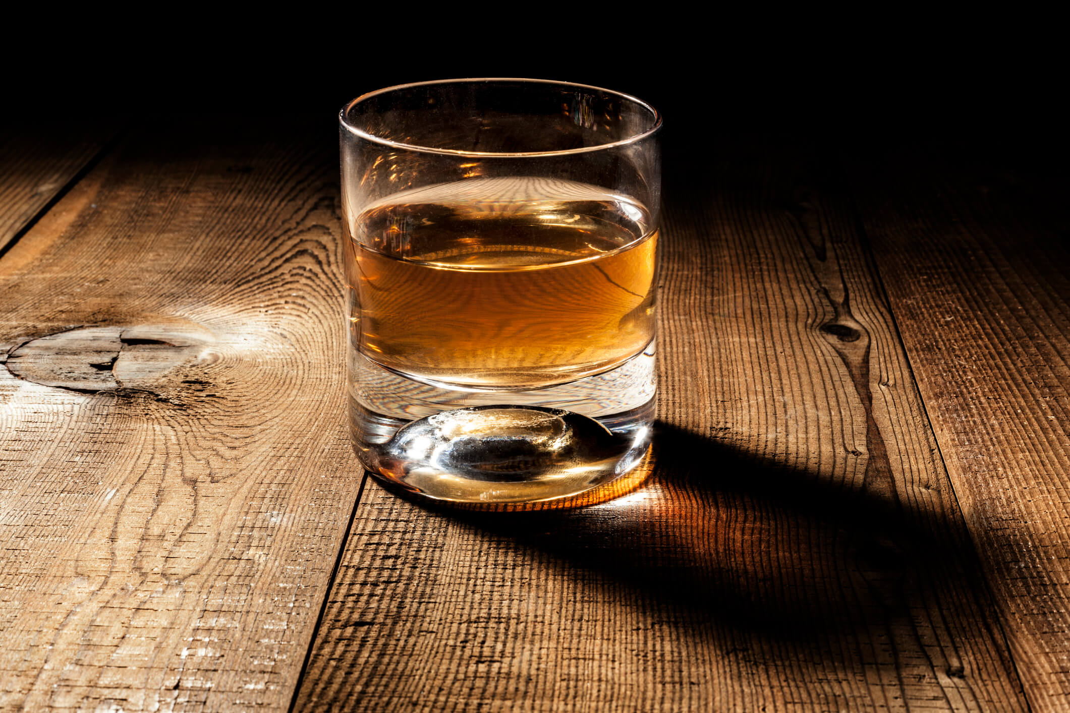 Brown spirit in a rocks glass against a dark background