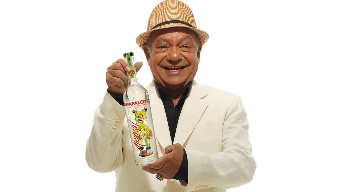 Cheech Marin holding a bottle of Tres Papalote mezcal
