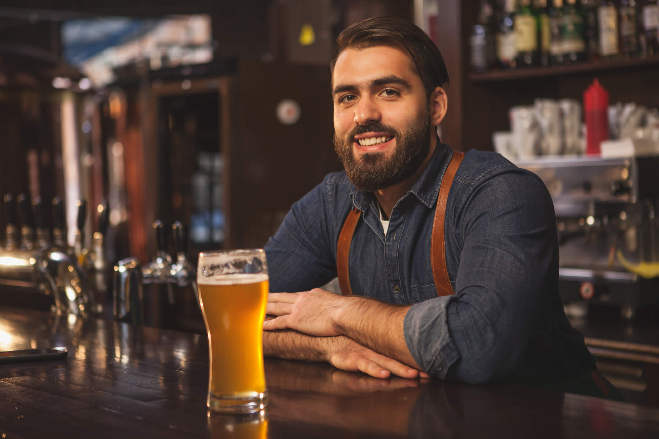 Smiling bartender serving a beer