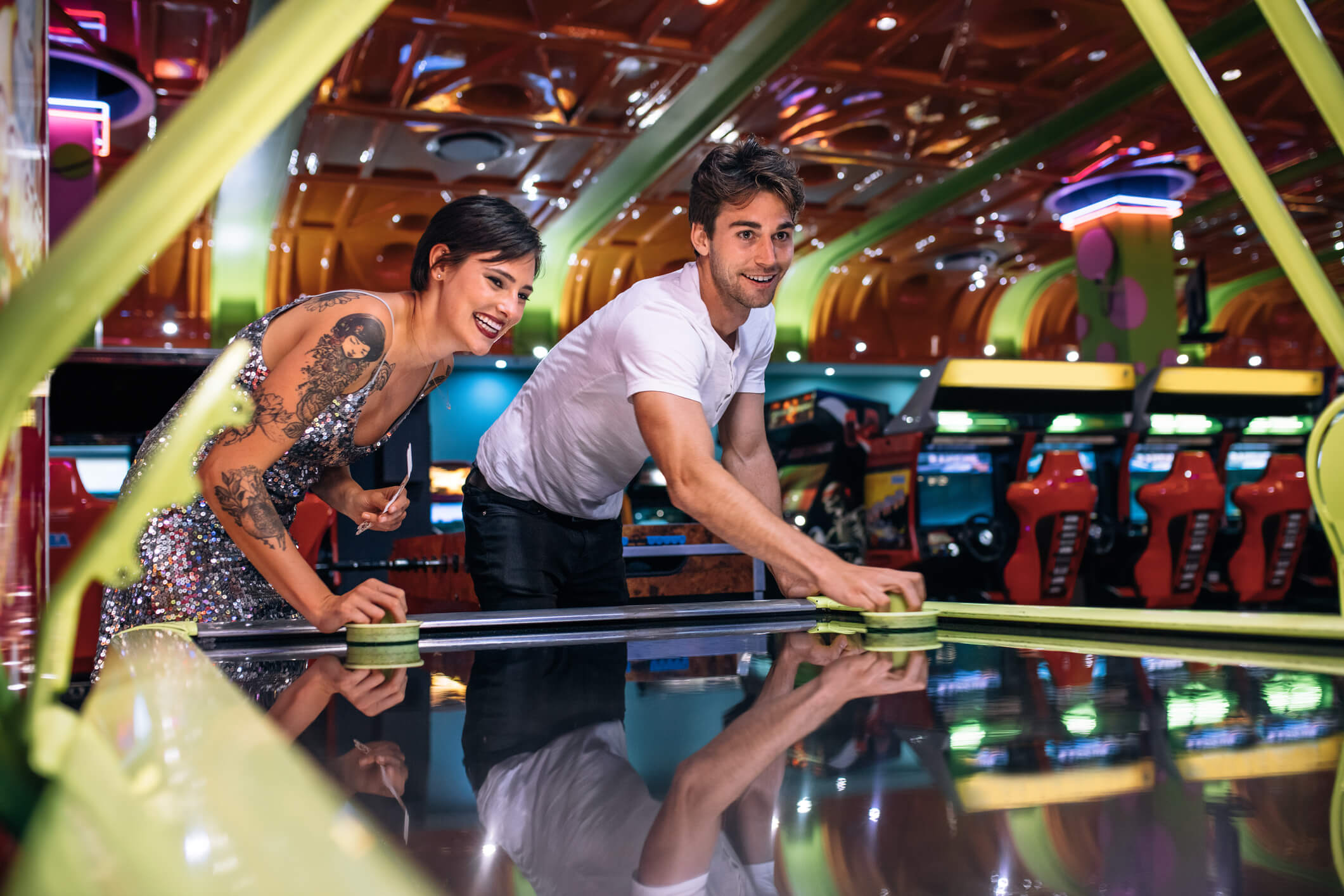 Couple playing air hockey at an arcade