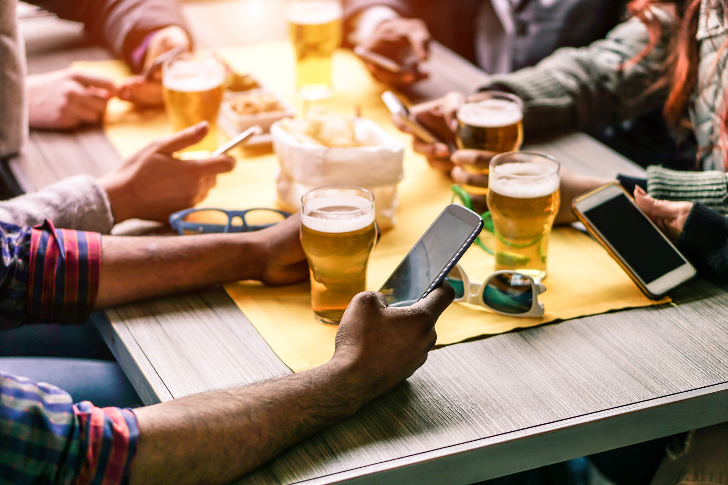 Group of people at a restaurant with food and beer on their phones