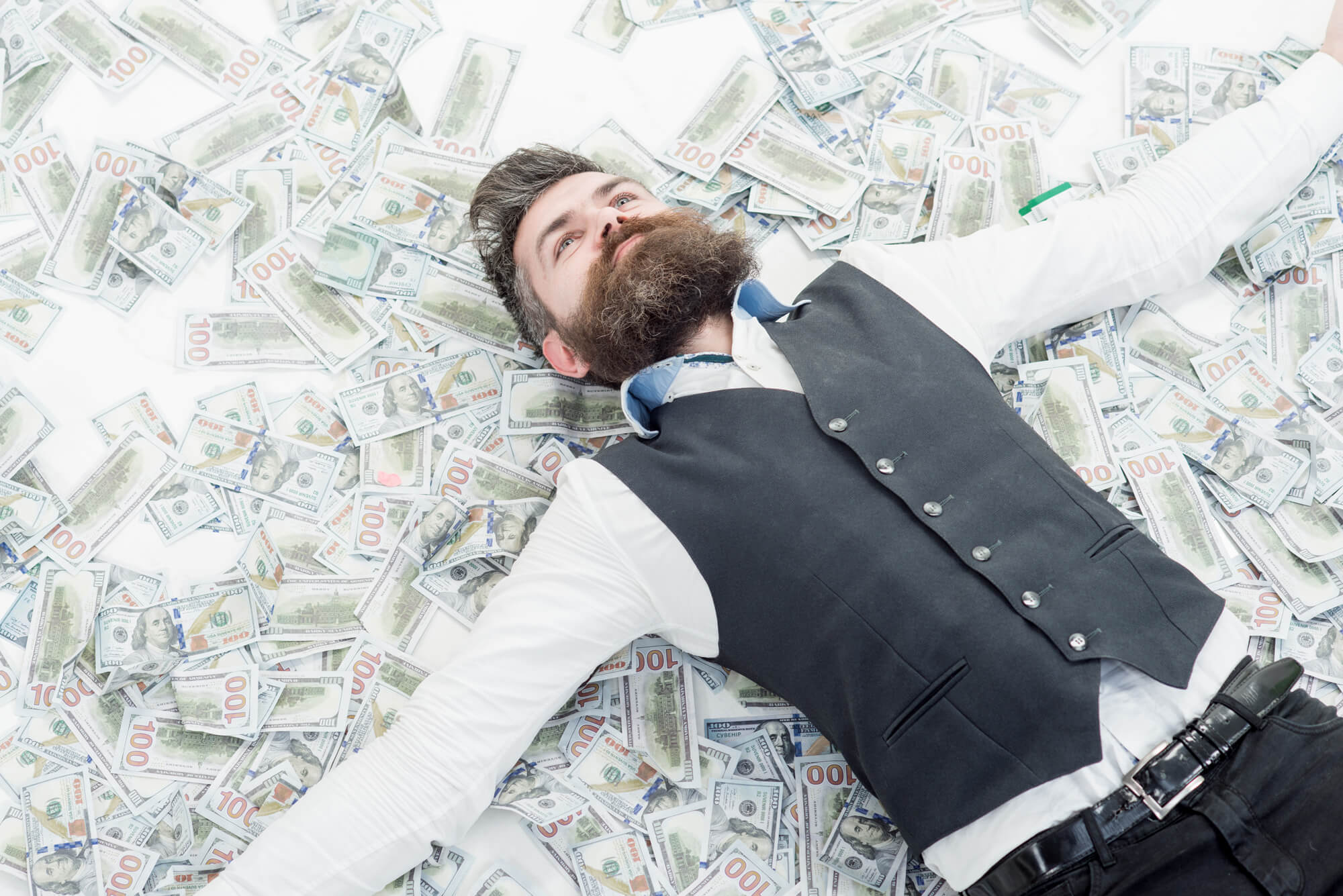 Bearded man lying on money