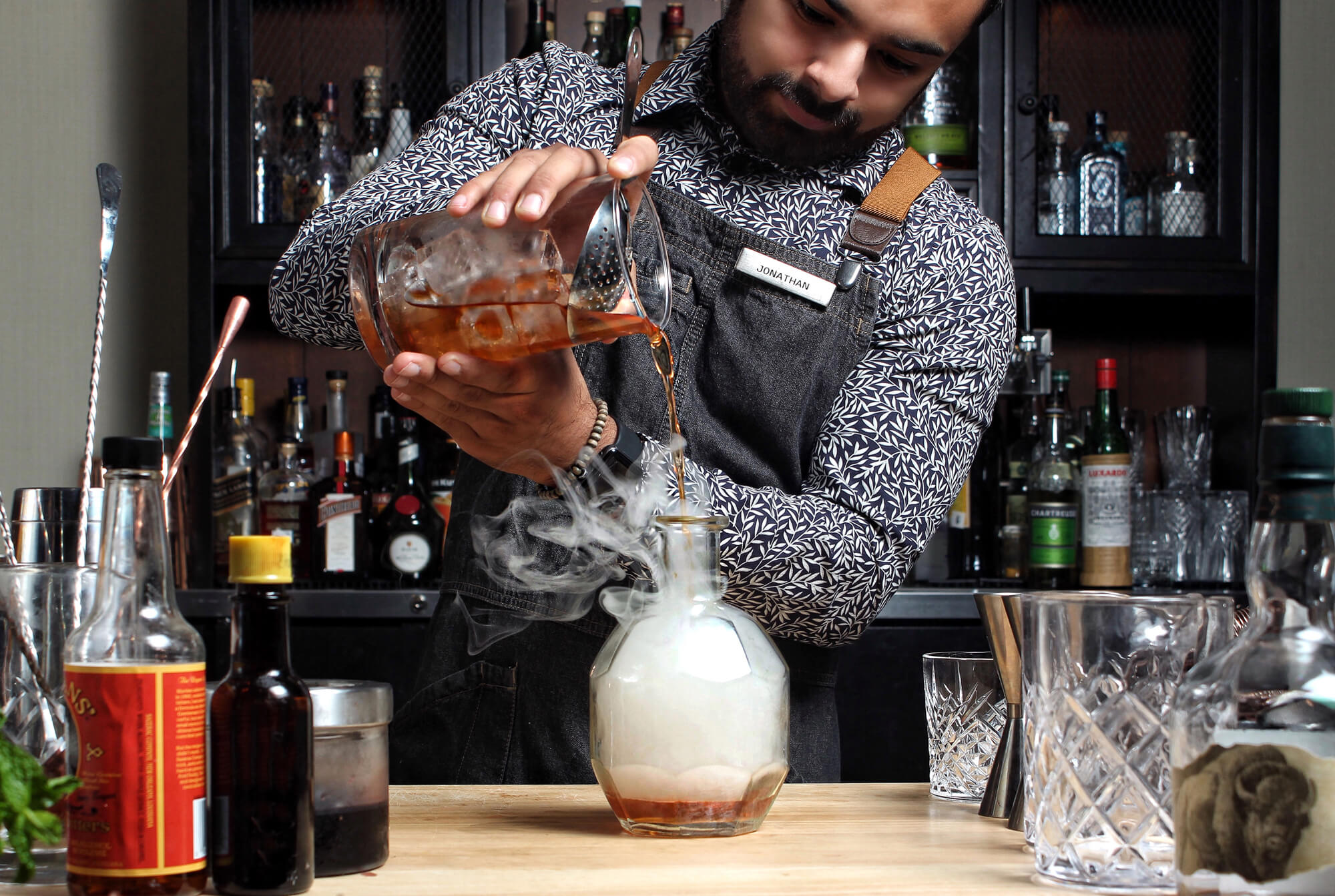 Bartender pouring smoking drink at YNK Lounge
