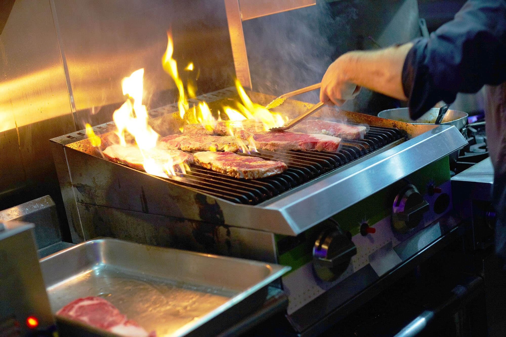 Chef grilling steaks in commercial kitchen