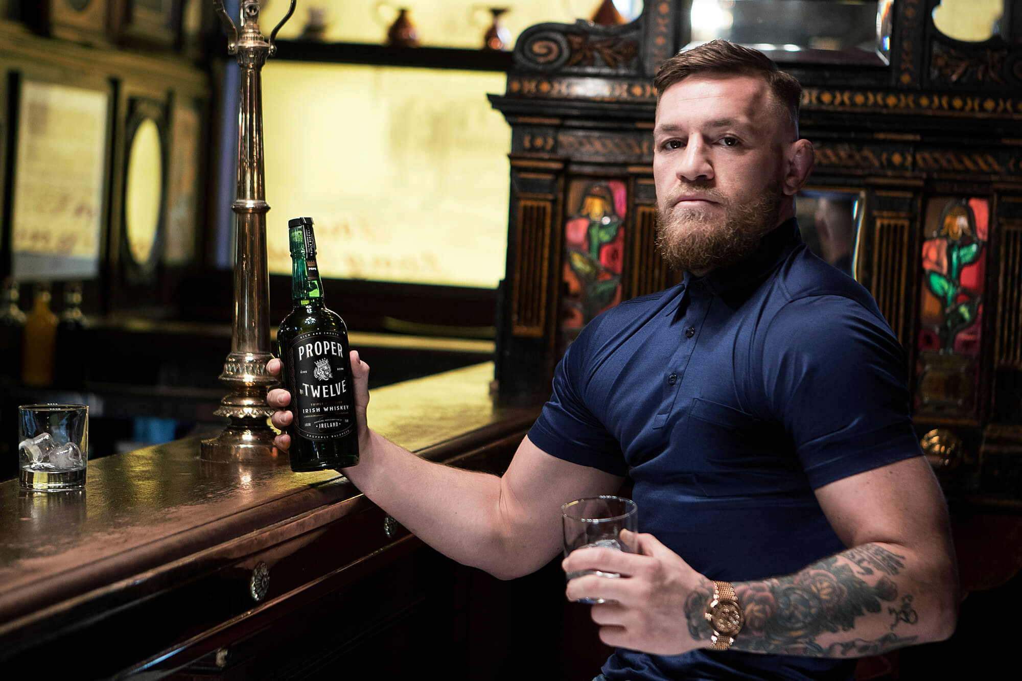 Conor McGregor with bottle of Proper No 12 Irish whiskey at bar