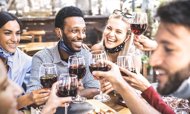 A group of friends celebrate over a glass of wine