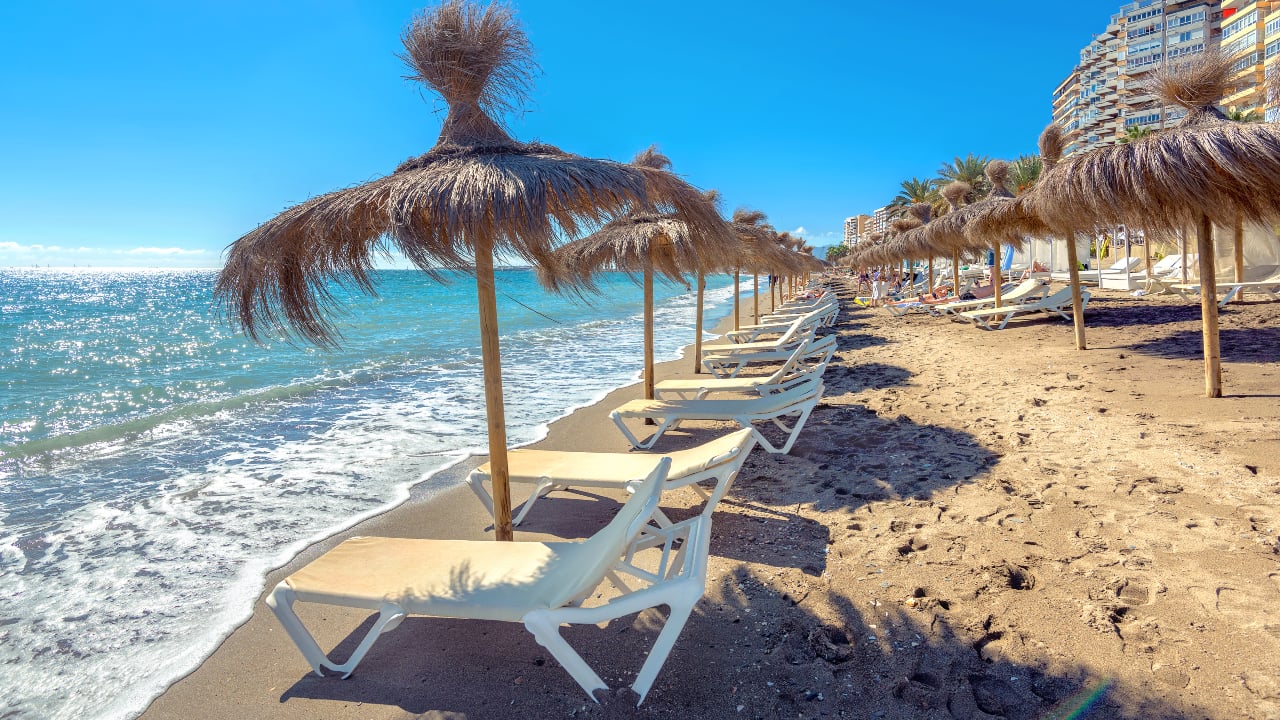Lounge chairs and straw umbrellas at the beach in Malaga Costa del Sol Andalusia Spain