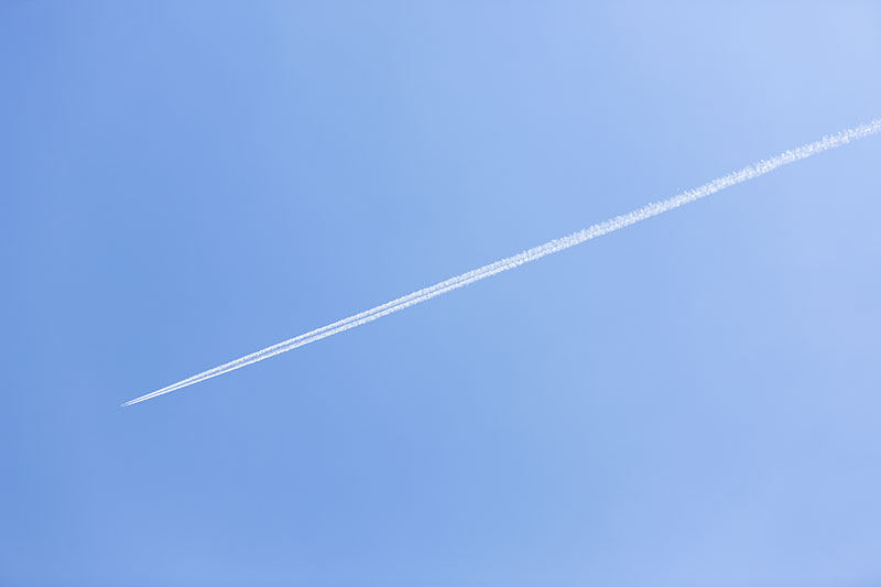 Long trail of jet plane on blue sky