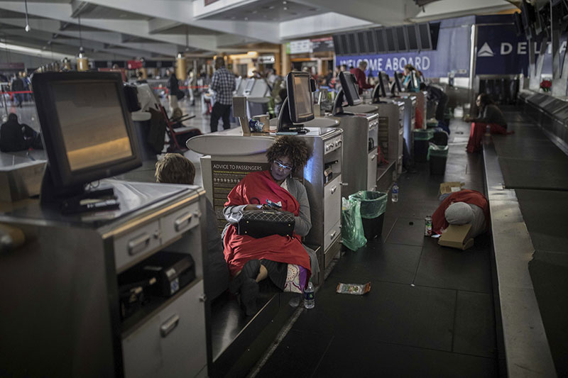 Passengers rest behind the ticket counter after the lights went out at Hartfield-Jackson Atlanta International Airport in Atl