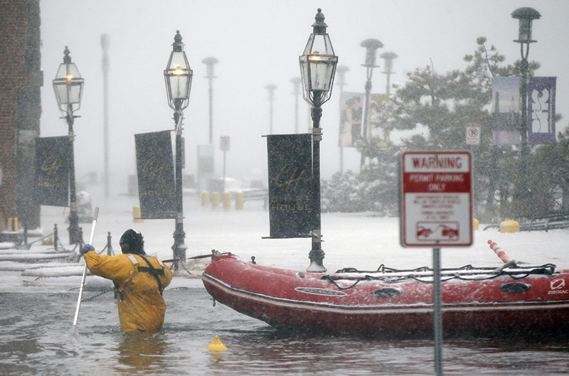 A Boston firefighter wades through flood waters from Boston Harbor on Long Wharf in Boston
