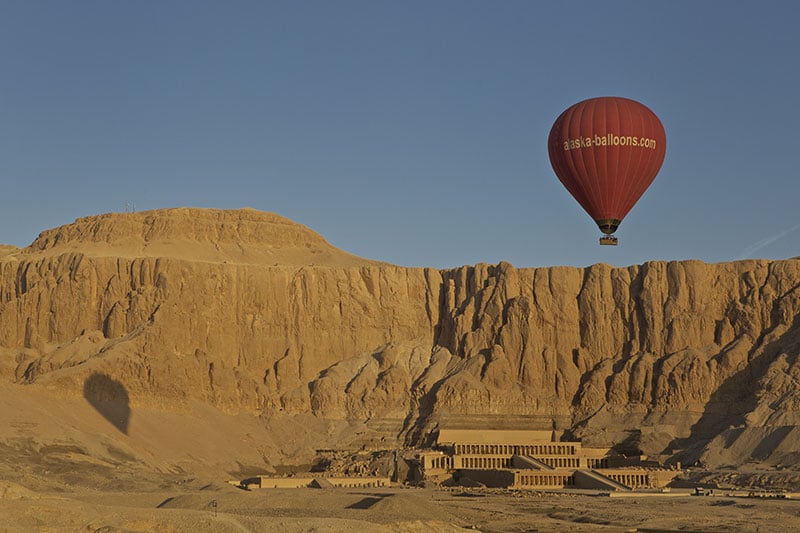 A hot-air balloon in flight over Egypts Valley Asasif and temple of Queen hatshepsut