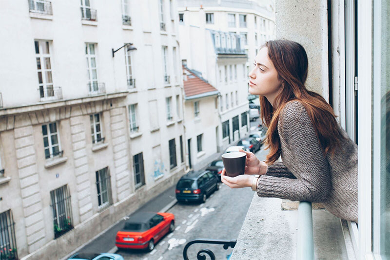 Young woman with coffee looking out over city street