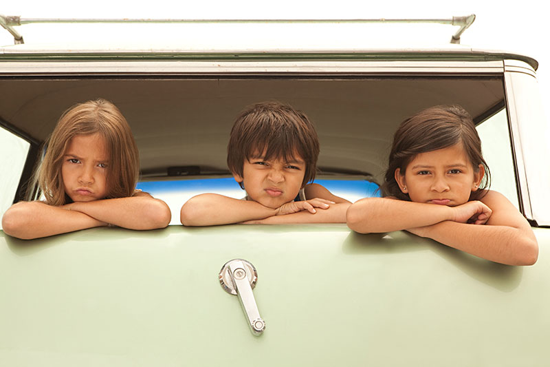 Three sullen children in back of estate car