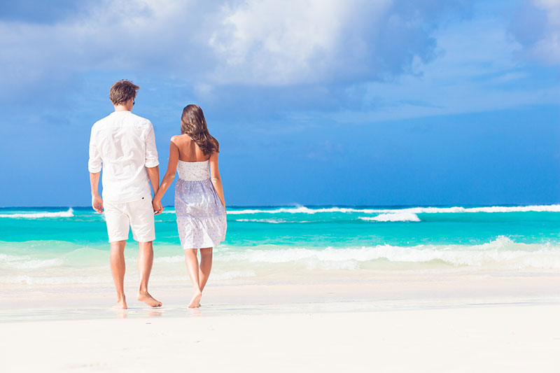 young happy couple in white at tropical beach honeymoon