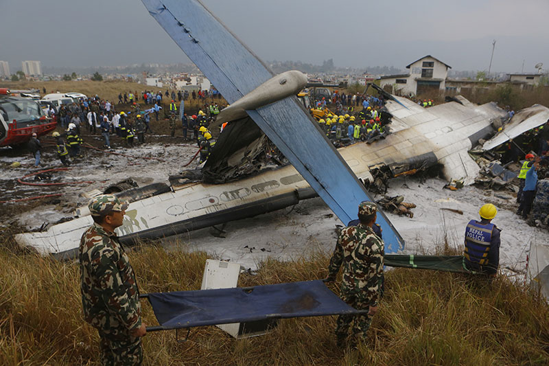 Nepalese rescuers work after a passenger plane from Bangladesh crashed at the airport in Kathmandu Nepal 