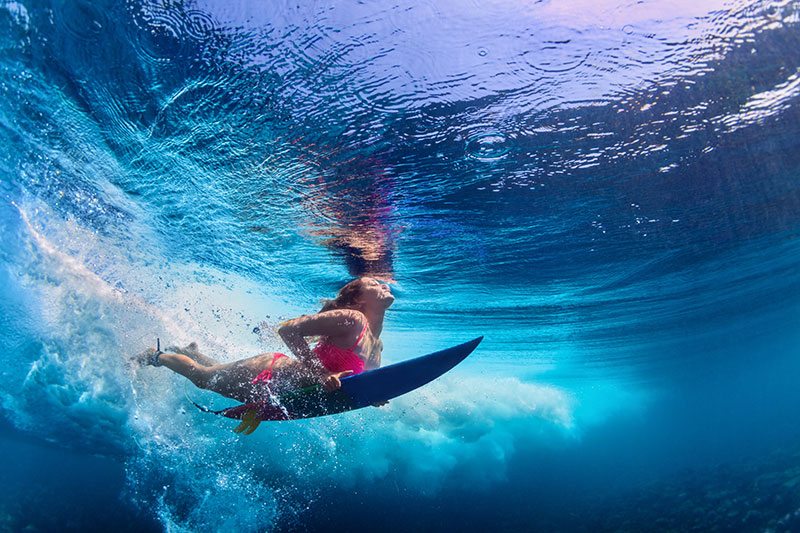 Surfer diving underwater with surf board