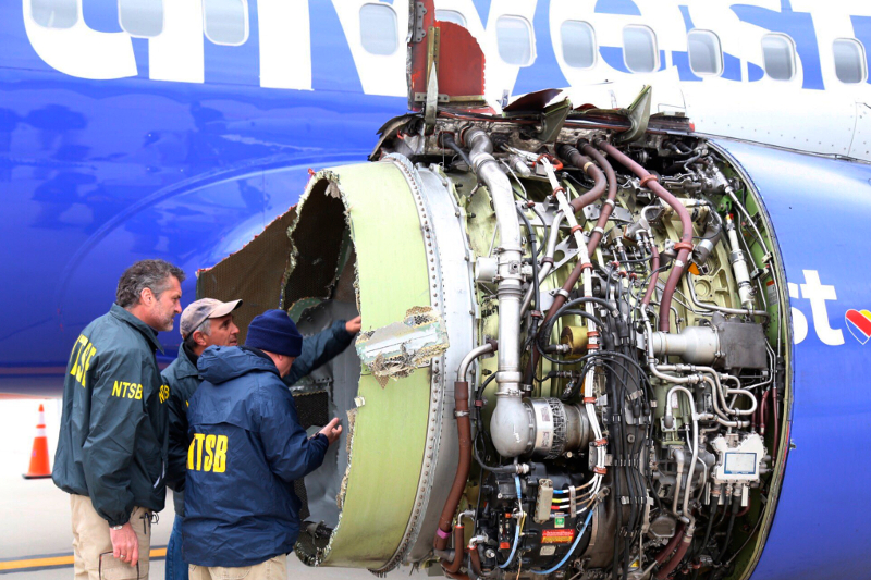 National Transportation Safety Board investigators examine damage to the engine of the Southwest Airlines plane that made an 
