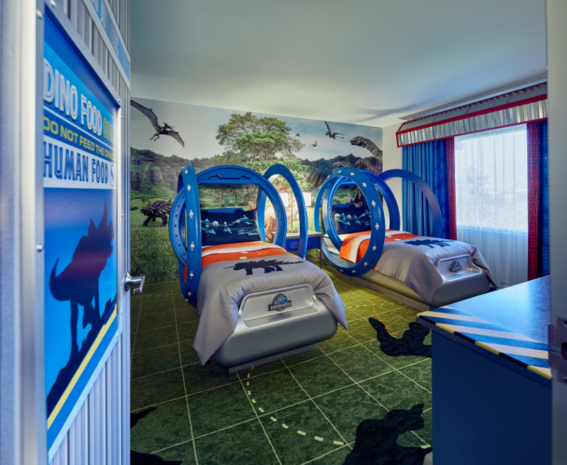 Two gyrosphere beds stand in front of a dinosaur mural in this kids themed room