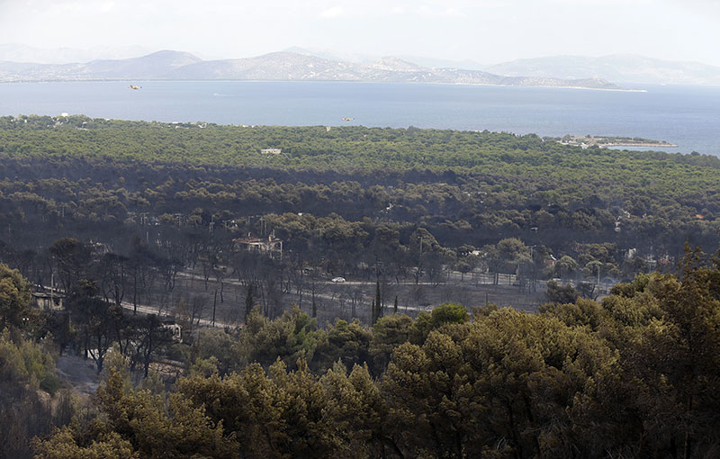 Firefighting planes fly over the trees near the fire damaged village of Neos Voutzas near Athens