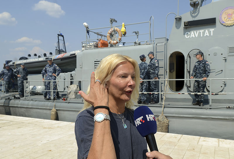 A woman who identified herself as Kay from England is interviewed by local media in front of a Croatian Coast Guard vessel i