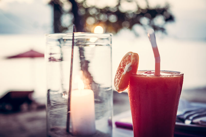Close up of a cocktail and a candle in a mason jar at a Caribbean beach bar