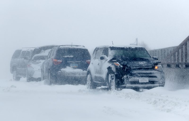 A string of wrecked vehicles sit on an overpass over Interstate 70 as a late winter storm packing hurricane-force winds and s