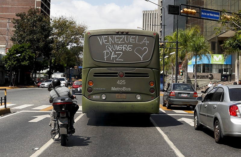 A bus with a message on its back window that reads in Spanish Venezuela wants peace drives through the streets in Caracas