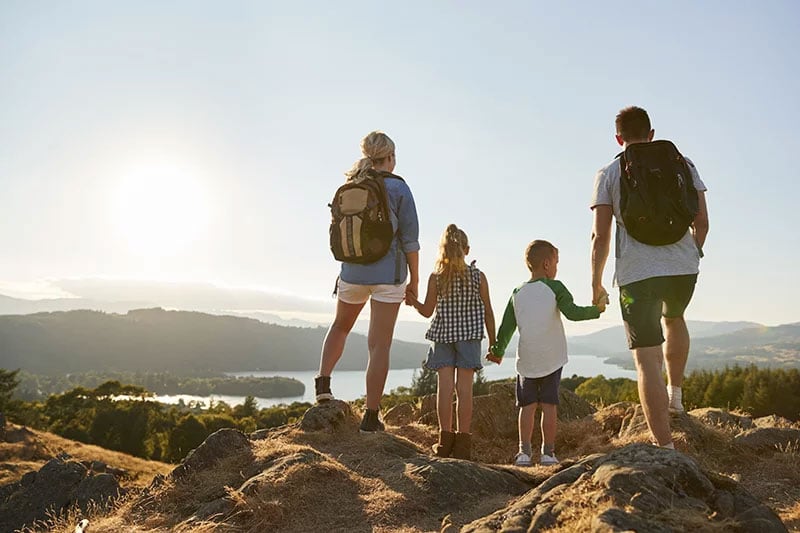 Family standing on a mountain overlooking a lake