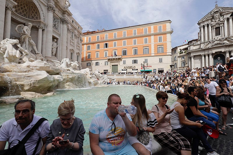 Tourist sit on the Trevi Fountain