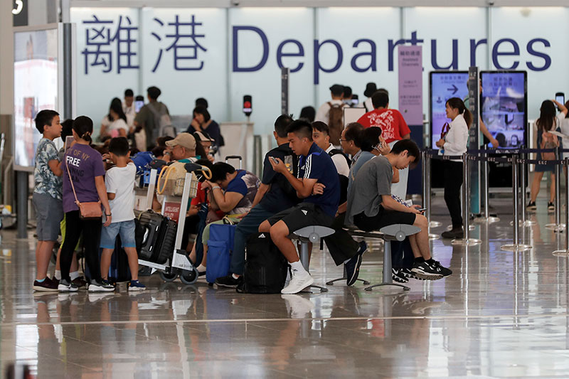 Travelers wait at the airport departure hall in Hong Kong