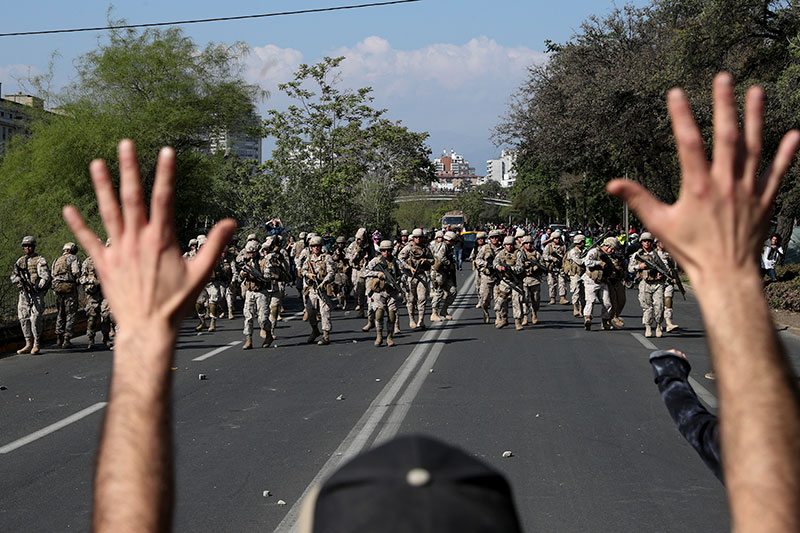 A demonstrator holds up his hands toward advancing soldiers during a protest as a state of emergency remains in effect in San