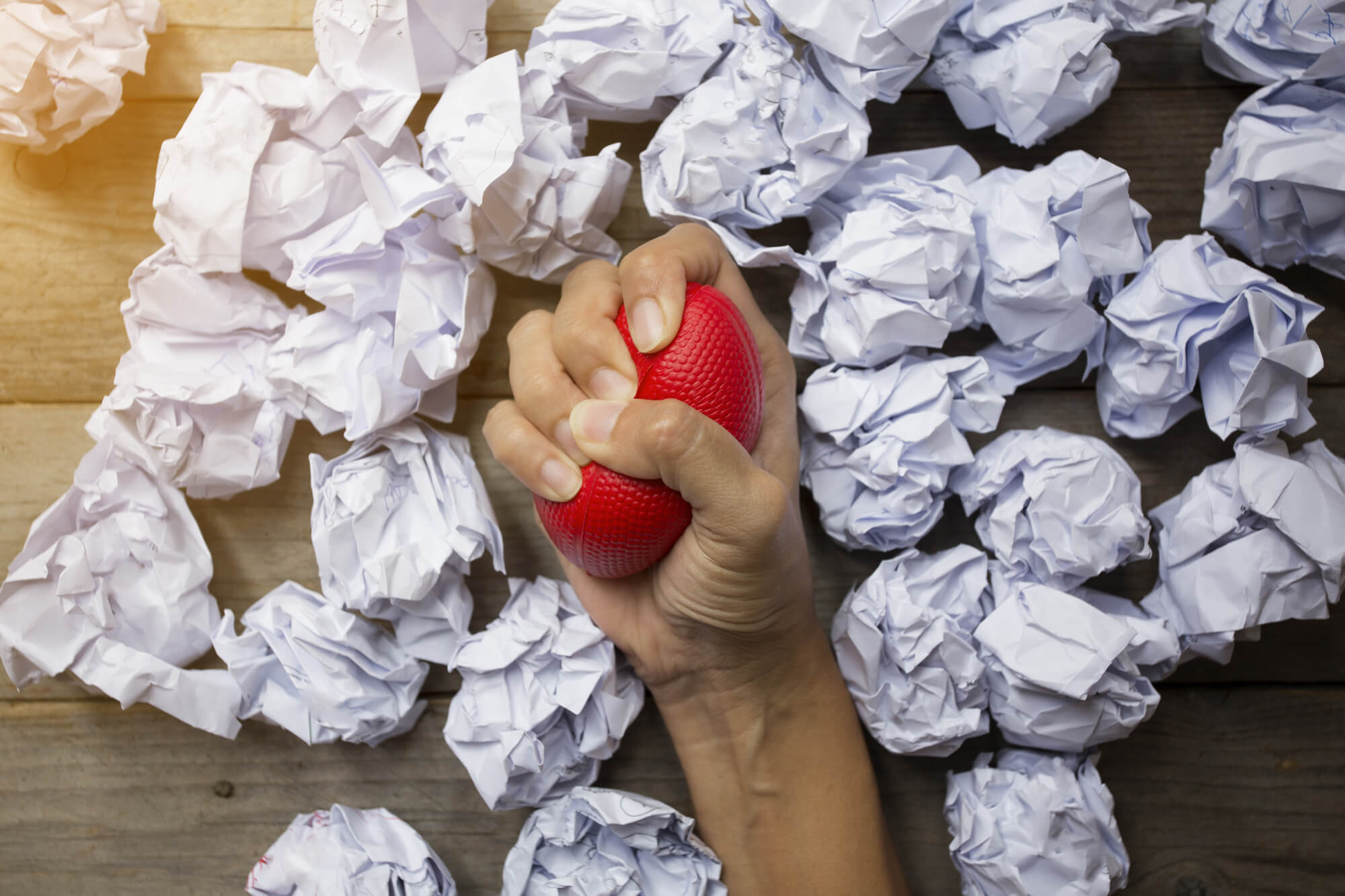 Stress ball squeezing surrounded by crumpled paper