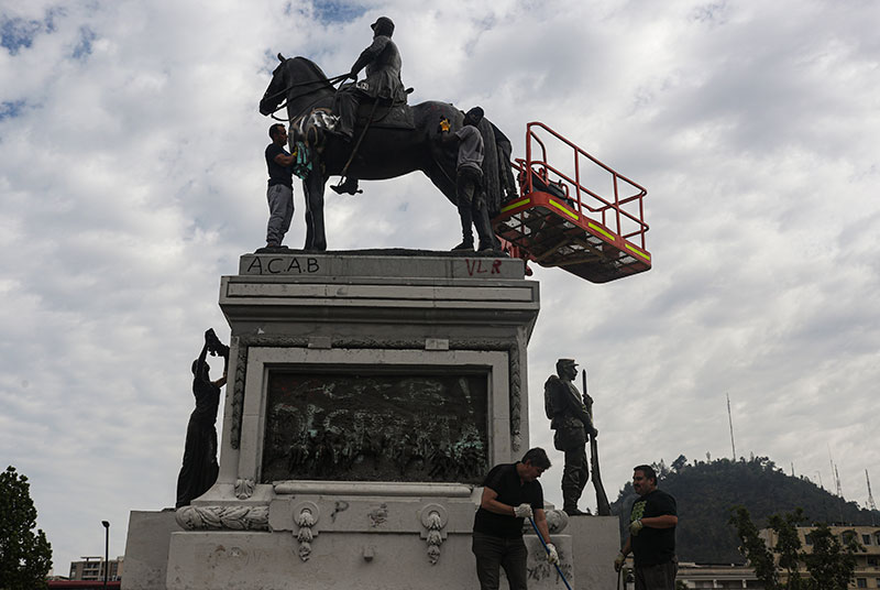 People clean the Gen Manuel Baquedano monument in Plaza Italia after it was vandalized amid days of demonstrations 