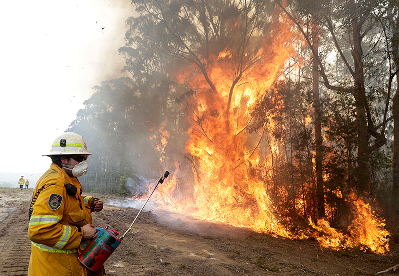 A firefighters backs away from the flames after lighting a controlled burn near Tomerong Australia Wednesday Jan 8 2020