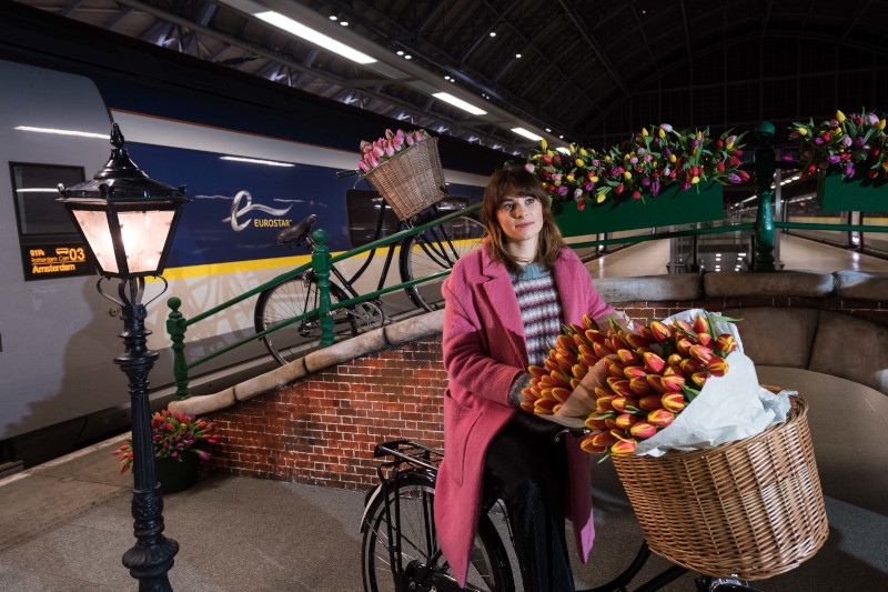 Image of woman on bicycle near trains 