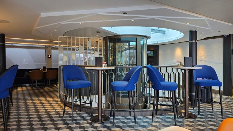 Some of the seating areas in The Bistro are high-top tables with blue upholstered chairs.