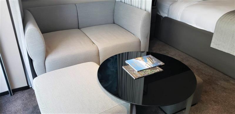 Light colored couch, round black table and two upholstered stools in the living area of #712, Scenic Eclipse II.