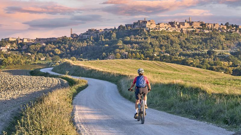 Woman riding electric bike towards Chianti, Tuscany, Italy