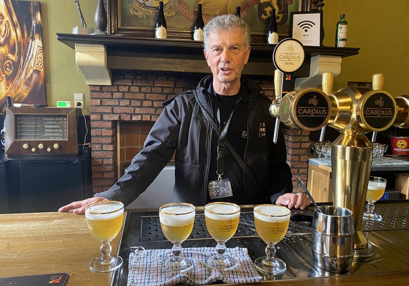 A man standing behind a bar with four beers and a tap