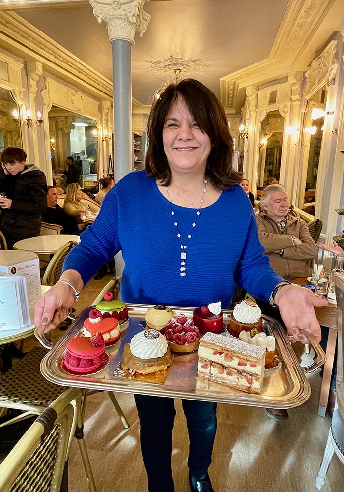 A woman holding a tray of desserts
