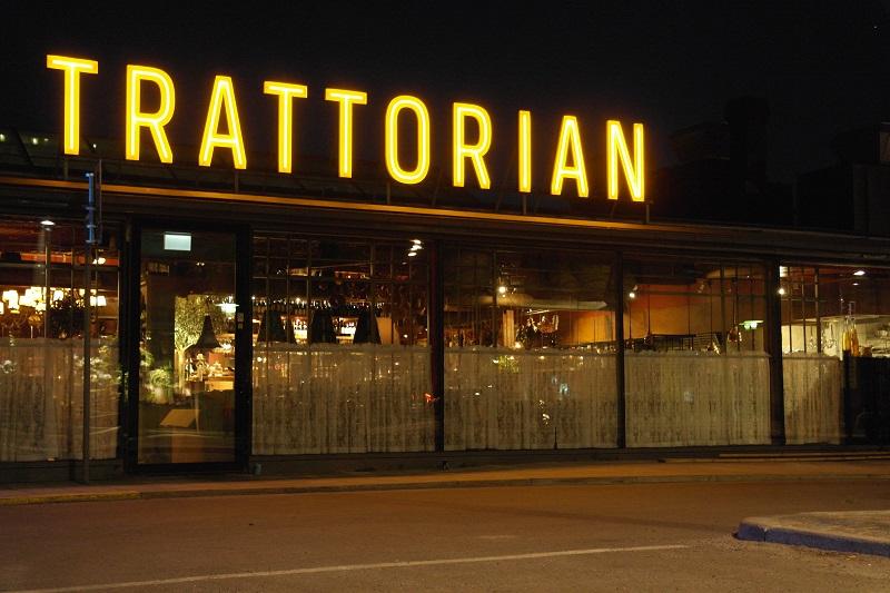 An illuminated restaurant sign reads Trattorian