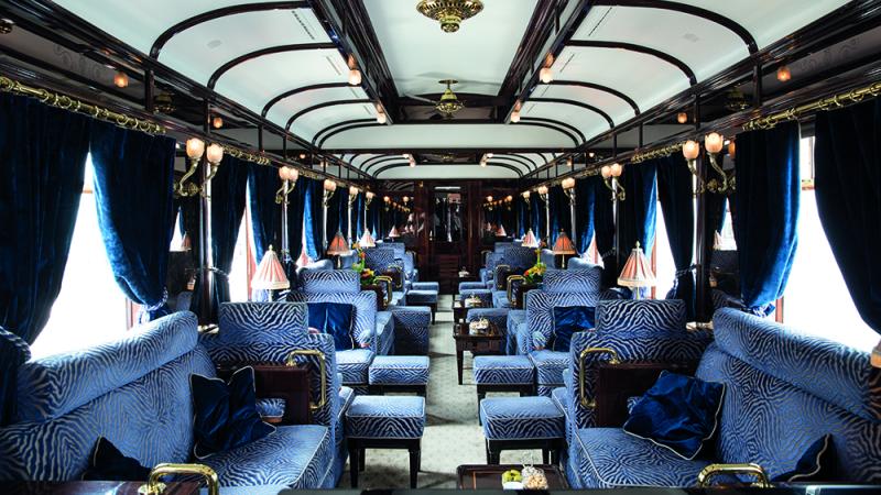 The bar cart with plush blue seating on a luxury train