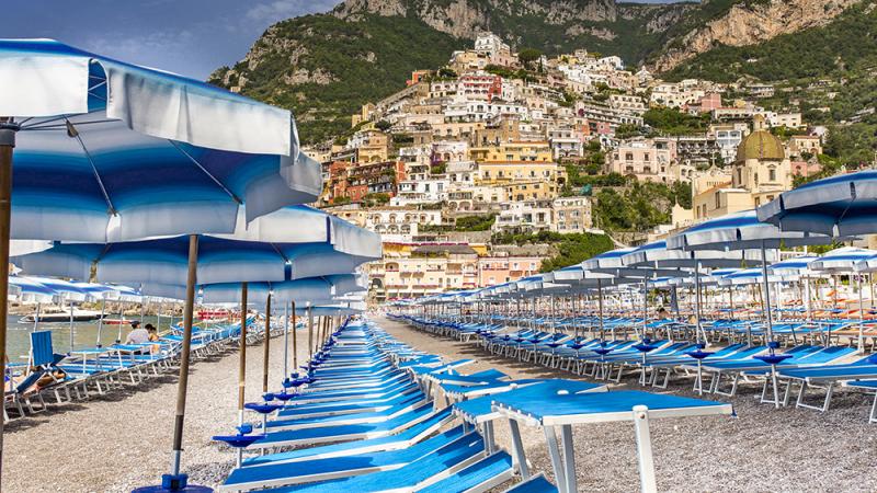 A beach with blue loungers and umbrellas in Positano, Italy