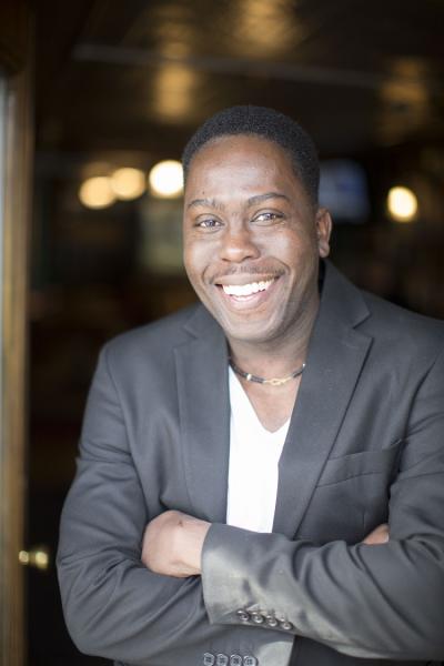 Loycent Gordon smiles from the doorway of his historical tavern in Queens, New York