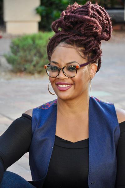 TaChelle Lawson smiles, while wearing glasses, a smart blue vest and elegant black top